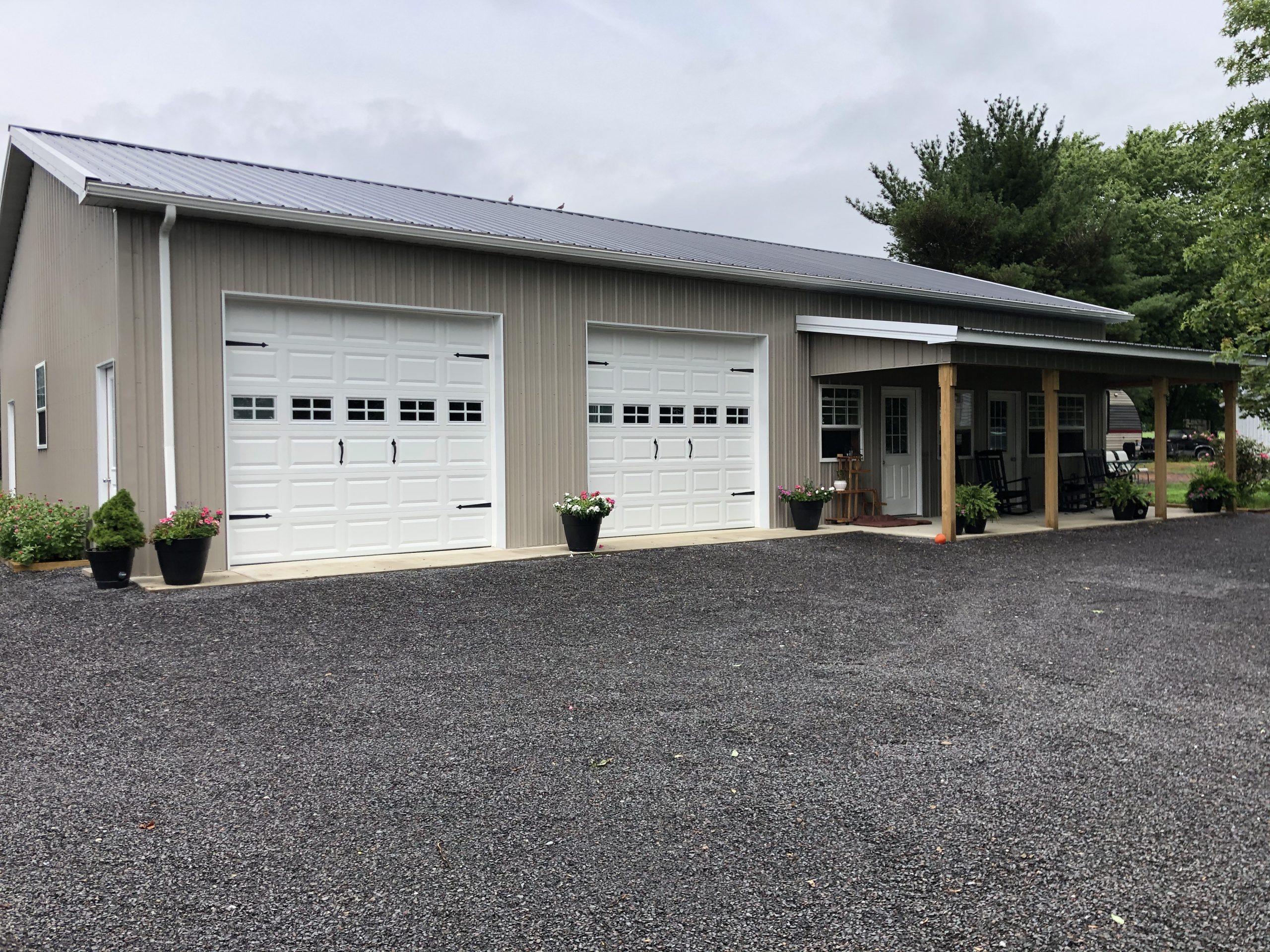 tan metal pole garage with small attached porch